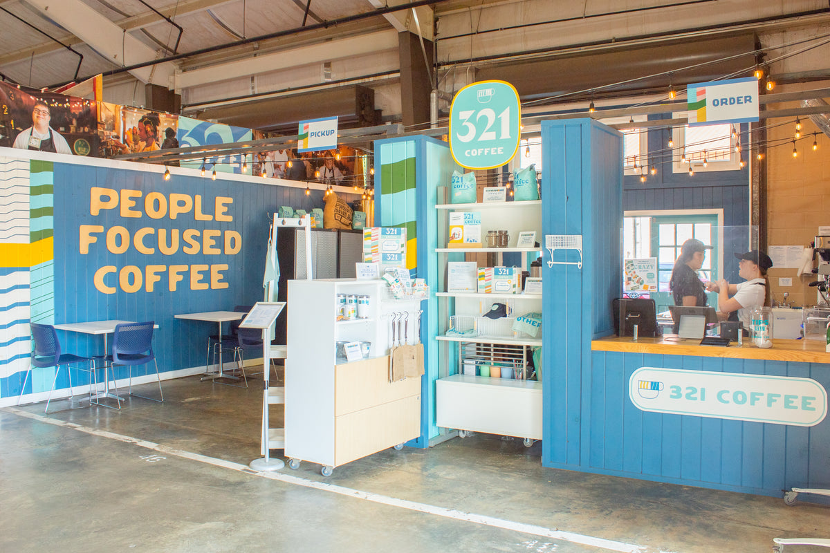 The Farmers Market shop is a large vendor stall inside the Market Shops building at the NC State Farmers Market. It features a large "People Focused Coffee" sign.