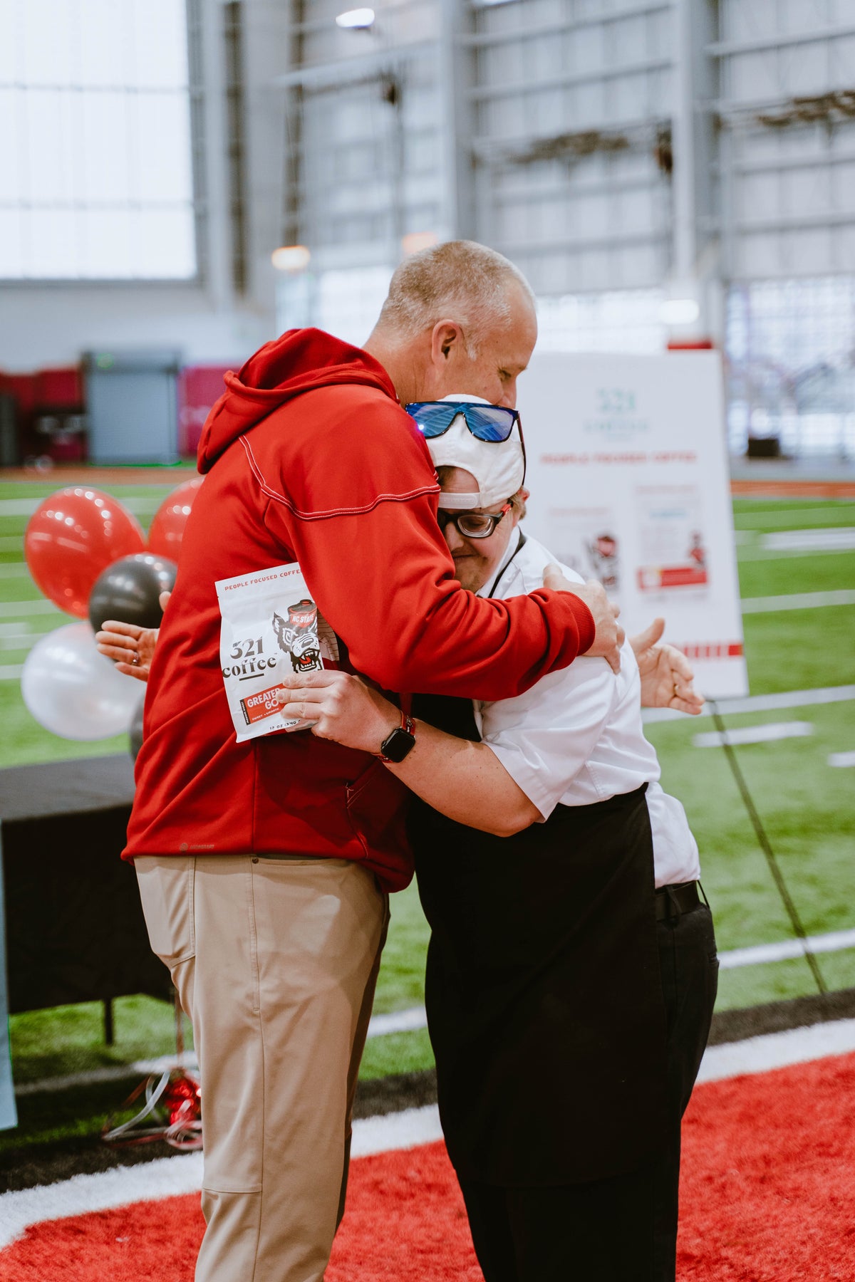 NC State Football coach Dave Doeren and barista Sam hug after the big reveal of the first bag of Greater Good coffee.