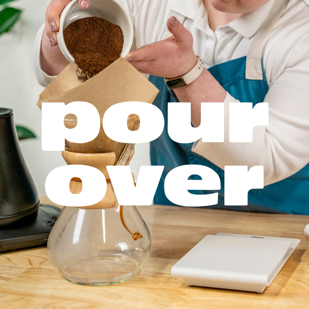 White text that reads "pour over" overlays a picture of a barista pouring coffee grounds into a Chemex filter.
